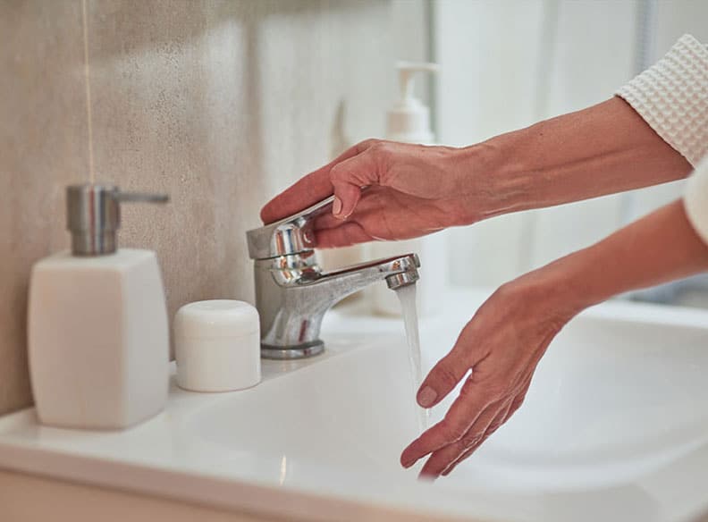 Une femme se lavant les mains à l'eau chaude