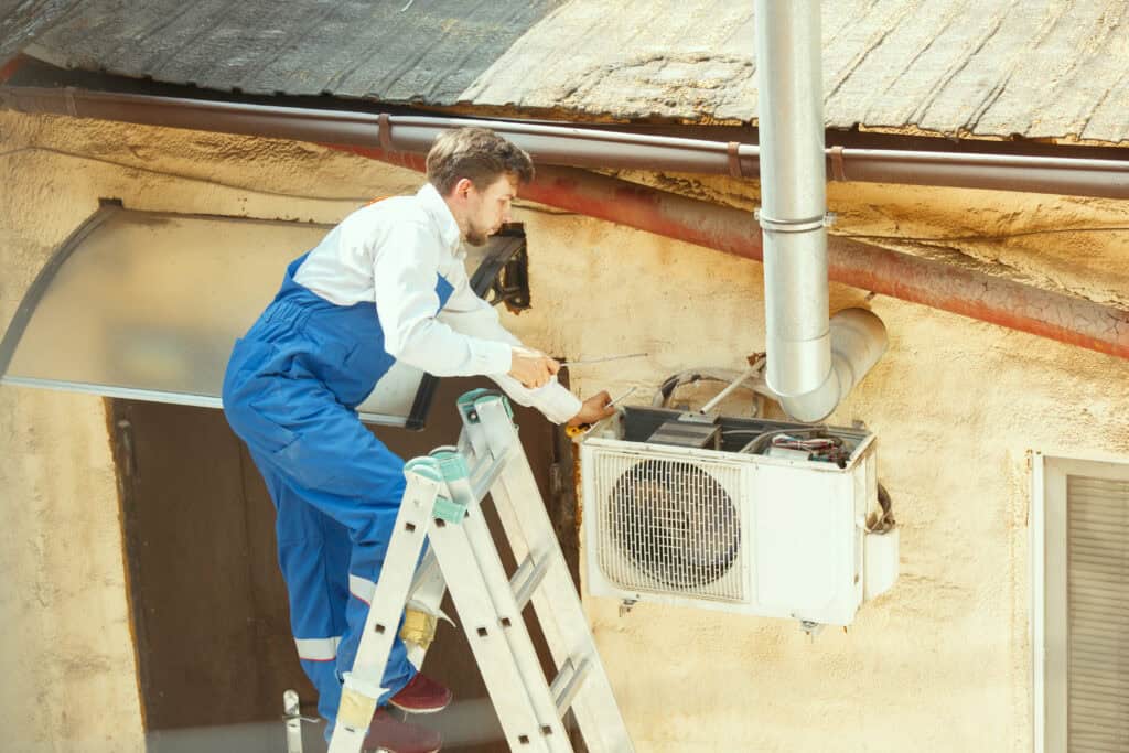 Technicien travaillant sur une unité de climatisation extérieur.