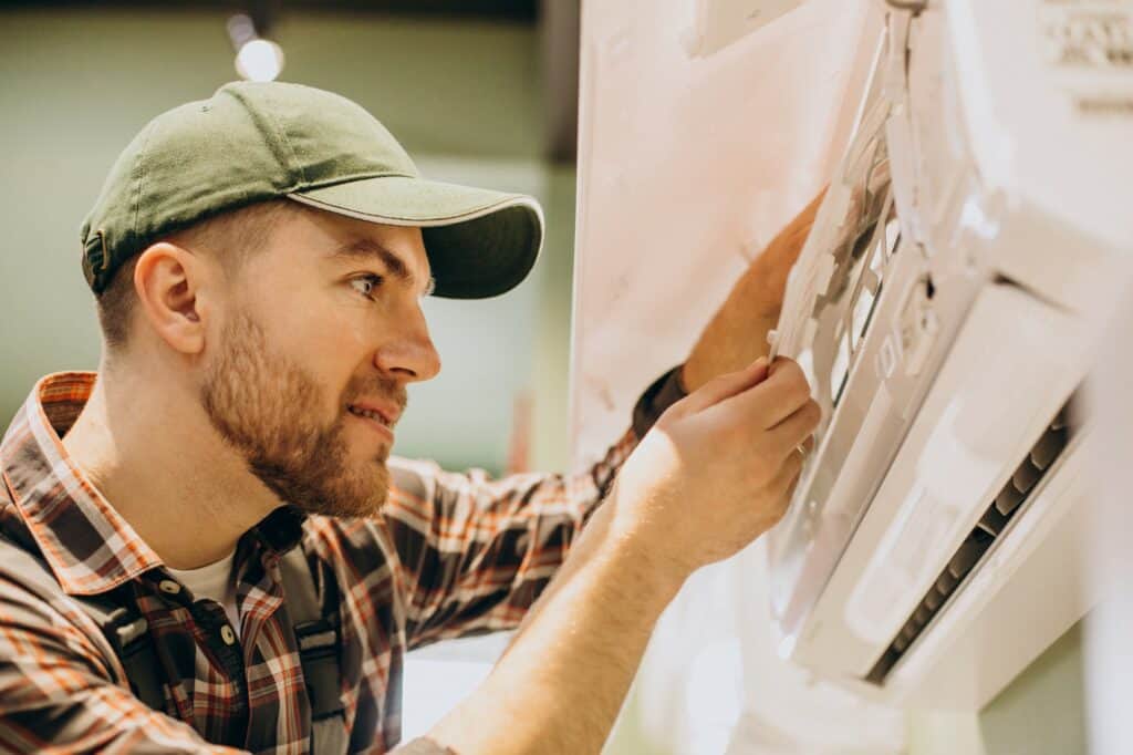 Un homme entrain de travailler sur la maintenance d'une climatisation réversible