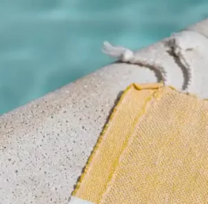 Fond d'écran été. Une serviette de plage jaune étalée au bord de la piscine