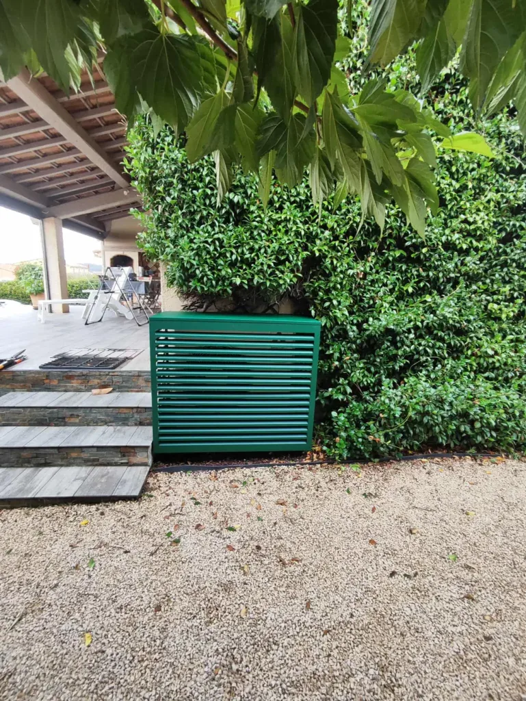 Cache-climatiseur extérieur en aluminium vert foncé installé par KALTEA dans un jardin à Aix-en-Provence, pour masquer une pompe à chaleur.